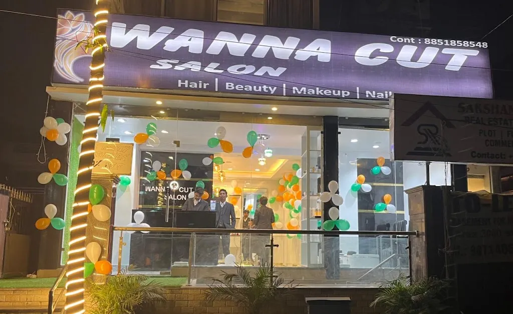 Wanna Cut Unisex Salon's storefront at night, signage lit